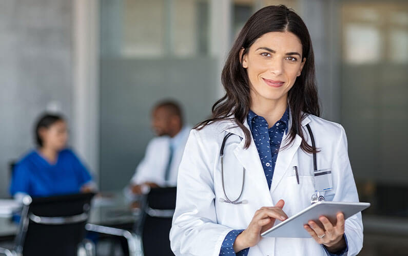 female doctor holding a tablet wearing a stethoscope and white coat