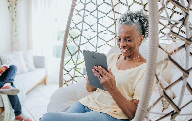 woman smiling sitting in a chair looking at a tablet