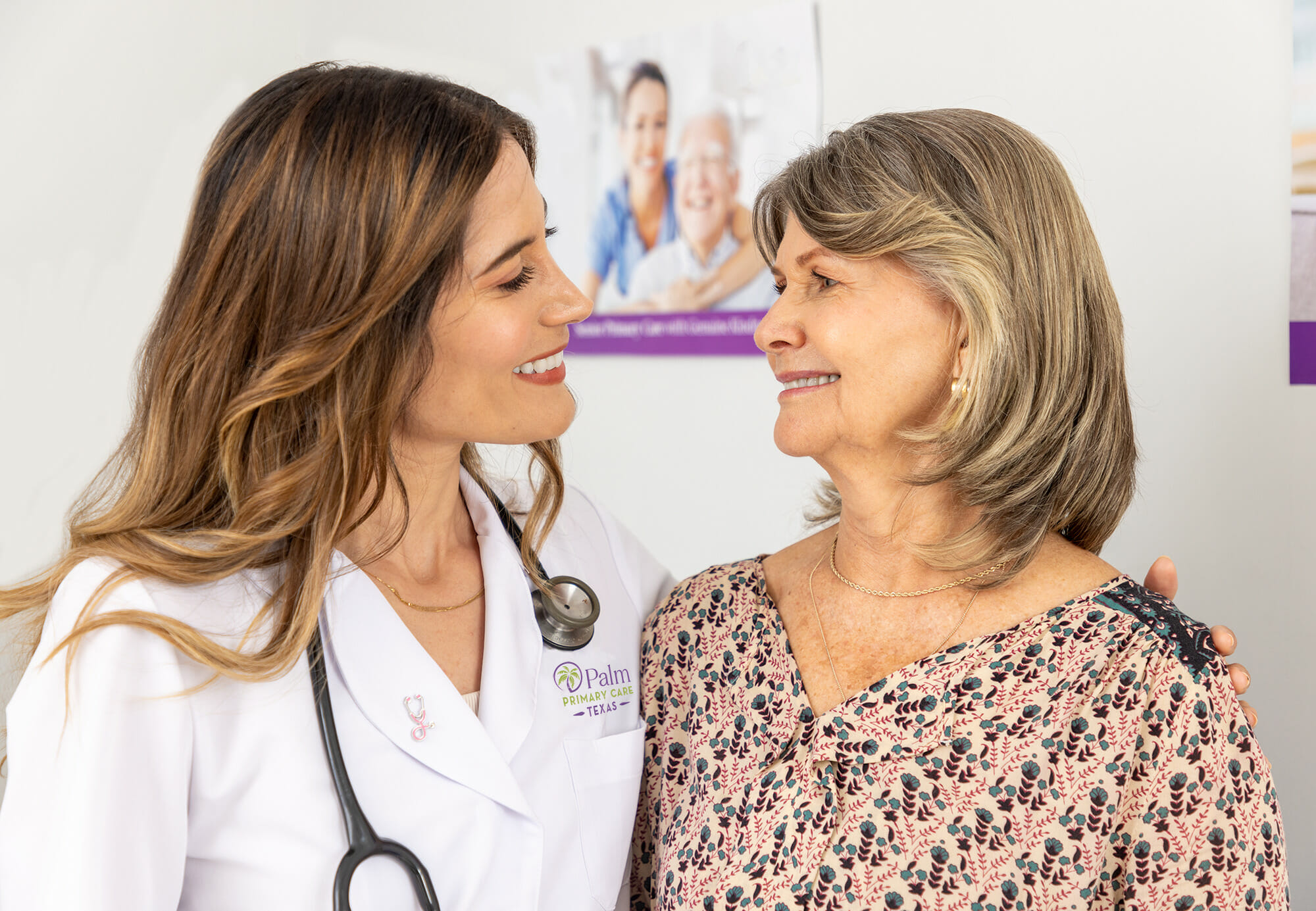Young woman doctor looking at and smiling with older woman patient