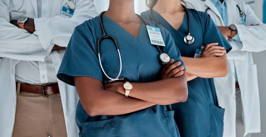 primary care physician standing with their arms crossed while working at a hospital
