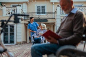 Caregiver takes elderly woman out in senior care center