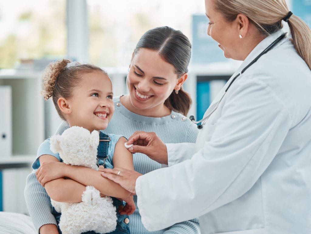 Shot of a family doctor using a cotton ball on a little girl's arm while administering an injection in a clinic