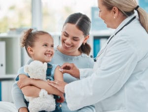 Shot of a family doctor using a cotton ball on a little girl's arm while administering an injection in a clinic