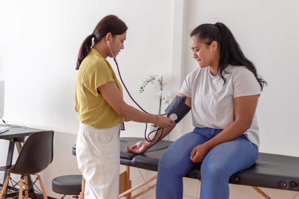 Woman having blood pressure measured by doctor in preventive medicne care