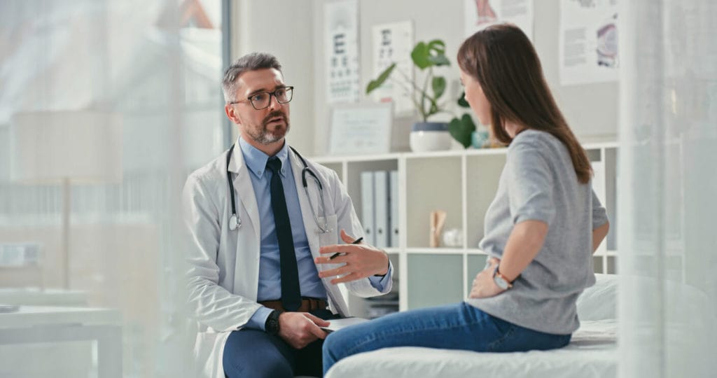Shot of a primary care physician sitting with his patient in the clinic and asking questions during a consultation