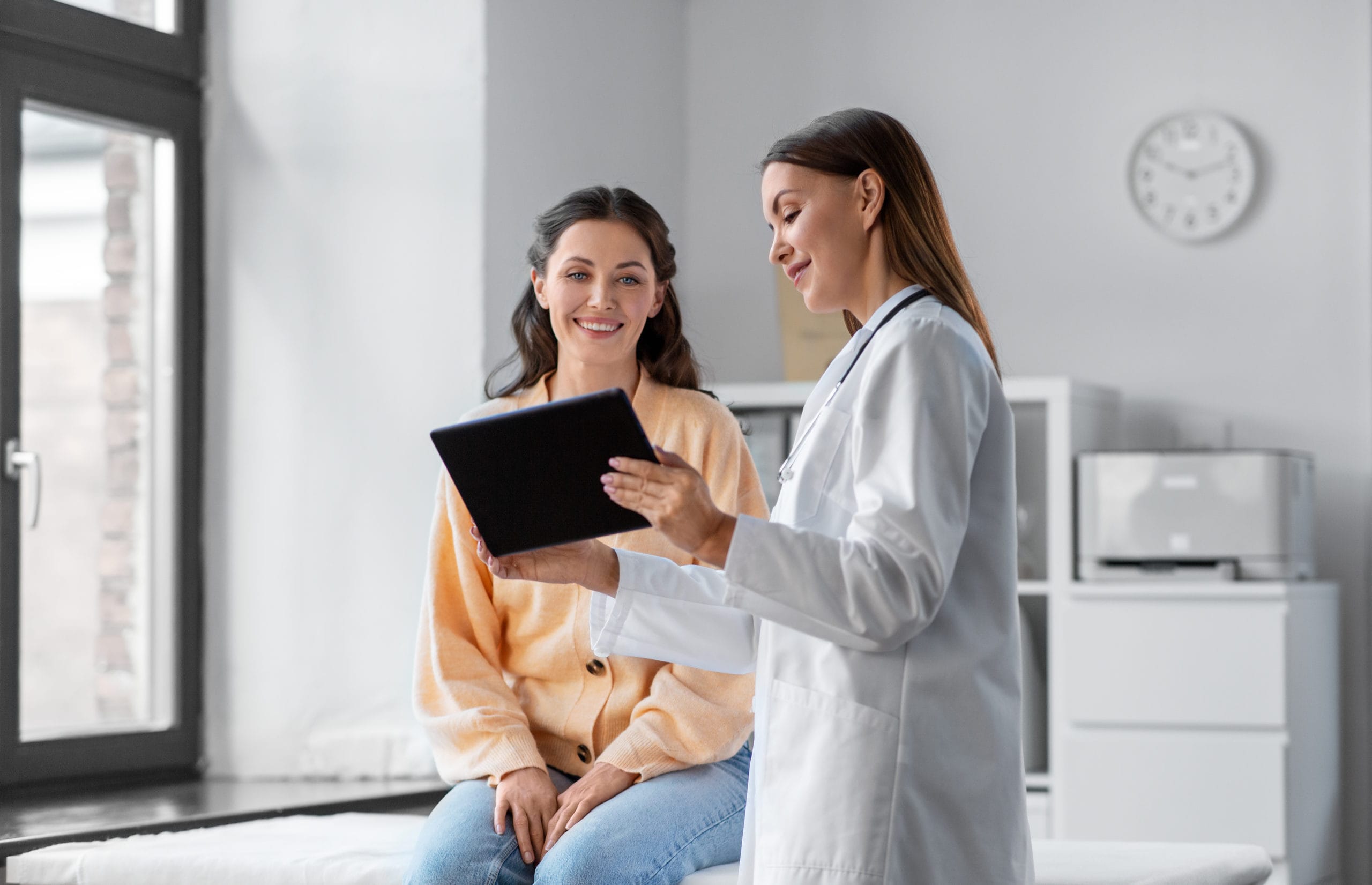 Two patients sitting on either side of a Palm Medical Centers physician. All of them are looking at a smartphone that the physician is holding and laughing.