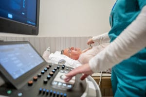 Senior male patient receiving echocardiogram to monitor heart disease.