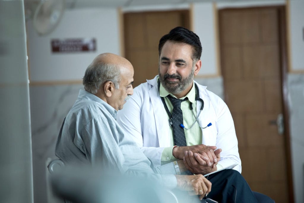 An image of a veteran elderly care doctor consulting with a senior patient in a clinic.