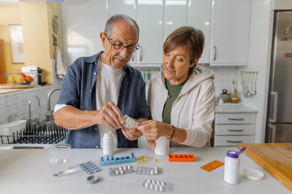 An image of a senior couple organizing their medications in the comfort of their home.