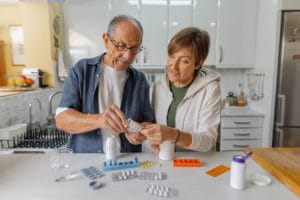 An image of a senior couple organizing their medications in the comfort of their home.