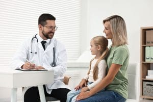 A family practice physician is consulting with a little girl and her mother in the hospital.