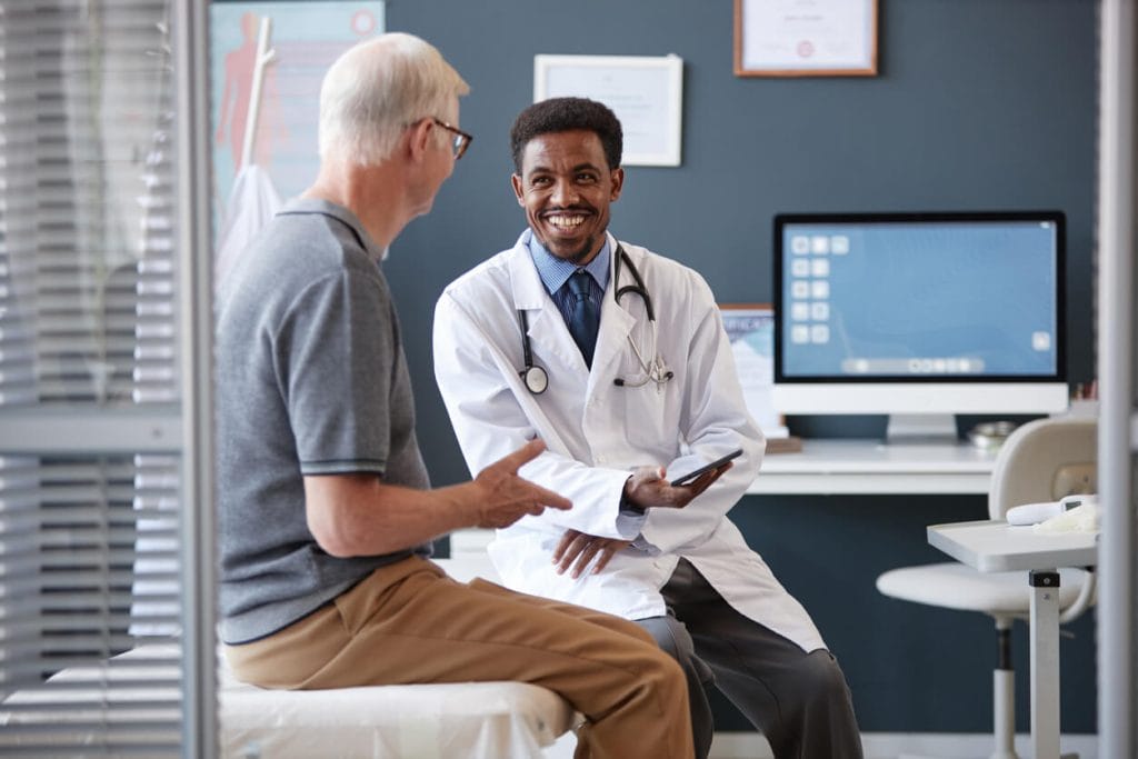A primary care doctor specializing in men's health talking to his older patient.