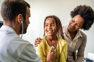 A family medicine doctor examining a little african girl at hospital.